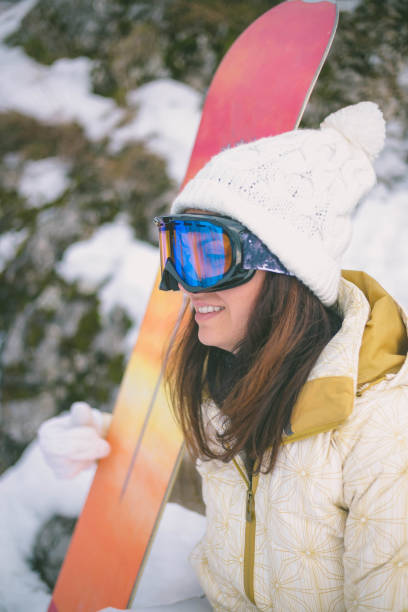 istock Woman holding snowboard with mountains in background 642448586