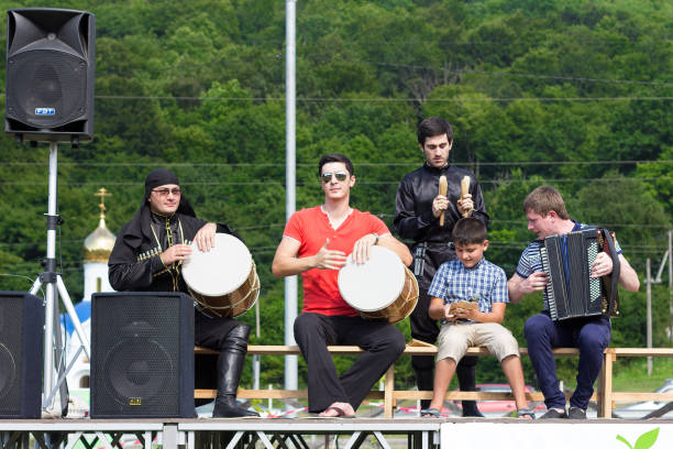 adygea, russia - july 25 2015: adyghe music ensemble of circassian national costumes playing the scene on the background of green forest ethnic festival in the mountains of adygea - circassian imagens e fotografias de stock