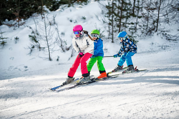 tres niños que se divierten esquiando juntos en día de invierno soleado - skiing snow skiing helmet fun fotografías e imágenes de stock