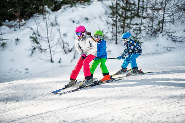 três crianças se divertindo esquiar juntos no dia ensolarado de inverno - skiing snow skiing helmet fun - fotografias e filmes do acervo