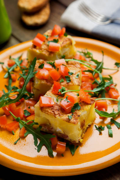 Potato tortilla prepared with arugula and tomatoes pieces stock photo