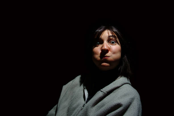 istock Young brunette woman blowing out her cheeks over black background 642469286