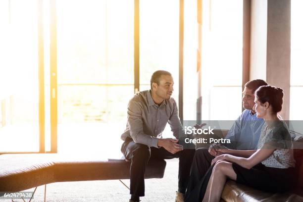 Confident Businessman Discussing With Couple Stock Photo - Download Image Now - Couple - Relationship, Financial Advisor, Meeting