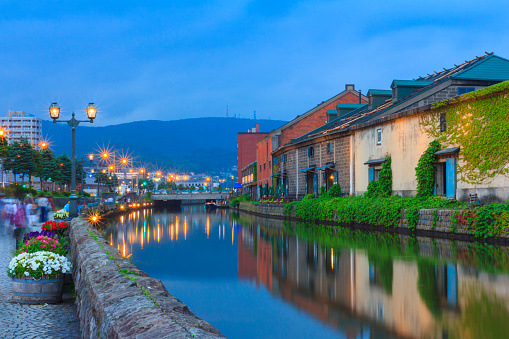 Otaru, Japan historic canal and warehouse in summer twilight time, people are walking alongside the canal, famous tourist attraction of Sapporo, Hokkaido.