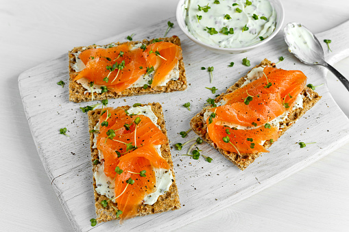 Homemade Crispbread toast with Smoked Salmon, Melted Cheese and cress salad. on white wooden board.