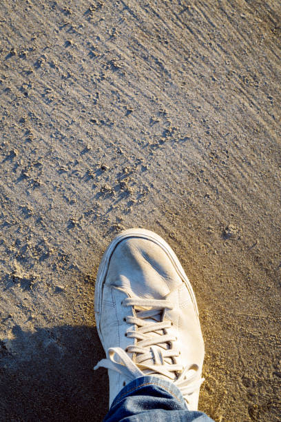 istock Sneakers shoes on beach sand, top view. 642493366