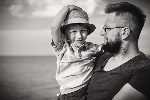 Dad and son spend time on the beach. Black and white.