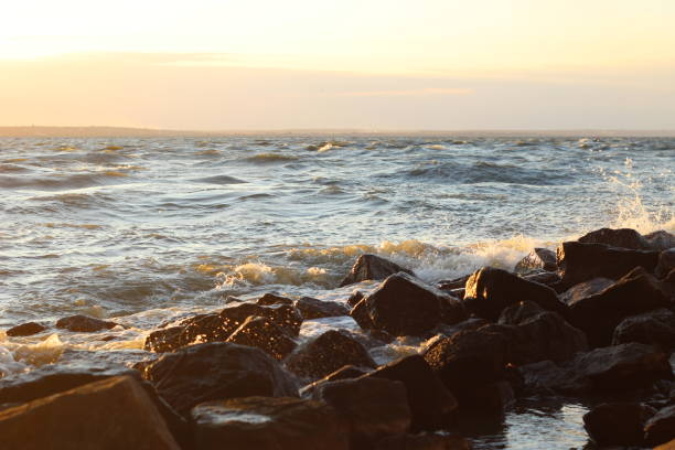 istock Waves beat crash rocks on lake shore in storm sunest 642508594