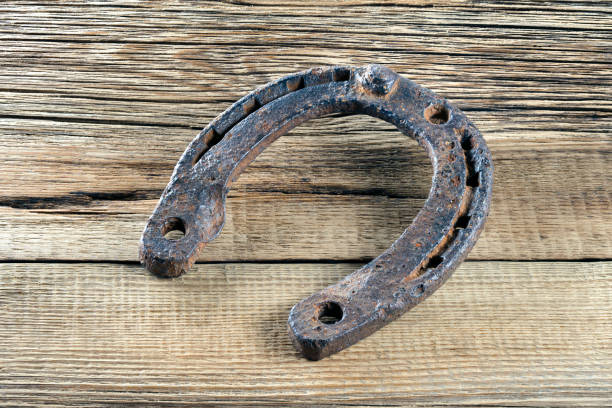 istock Old rusty horseshoe hanging on a wooden background 642524328