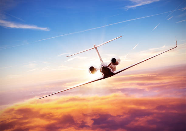 Private jet plane flying above clouds in beautiful sunset.