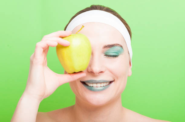 istock Young woman covering her eye with an apple 642536078