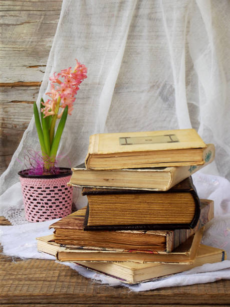 istock Stack of old hardback books and hyacinth on wooden background. Selective focus. Copy space 642543754