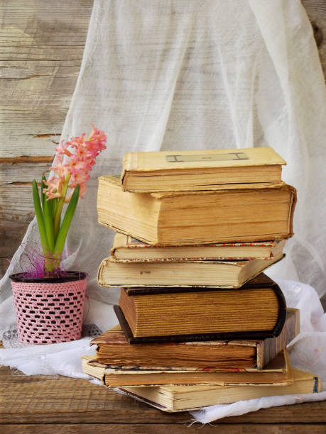 istock Stack of old hardback books and hyacinth on wooden background. Selective focus. Copy space 642543812