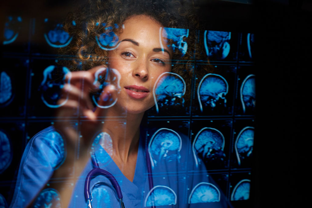 a female doctor or surgeon is analysing the digitally generated scans of a human brain