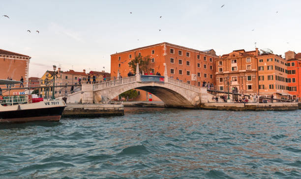 Venice cityscape Castello district at sunset, Italy. Unrecognized people walk along waterfront bridge in Castello district with Navy Historic Museum at sunset. Venice is one of world most popular tourist destinations. venice biennale stock pictures, royalty-free photos & images