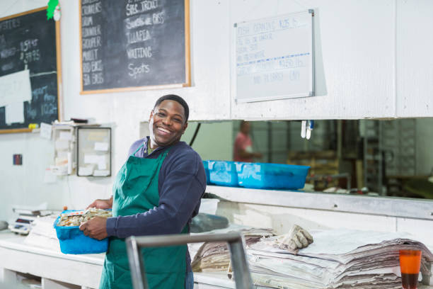 uomo afroamericano che lavora nel mercato del pesce - service occupation candid small business carrying foto e immagini stock