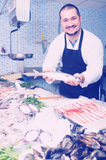 istock Positive seller in black apron showing fish 642631924
