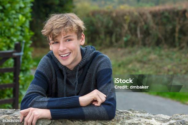 Young Happy Laughing Smiling Teenager Male Boy Blond Child Outside Leaning On A Wall In Autumn Fall Sunshine Stock Photo - Download Image Now