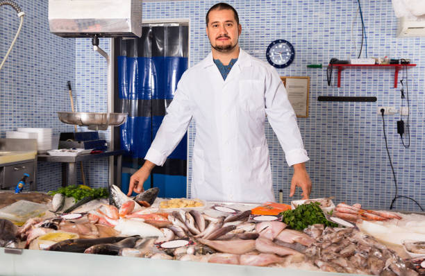 istock Man in white cover-slut showing fish on counter 642634922