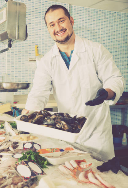 istock Seller stands behind counter  with big mussels 642635008