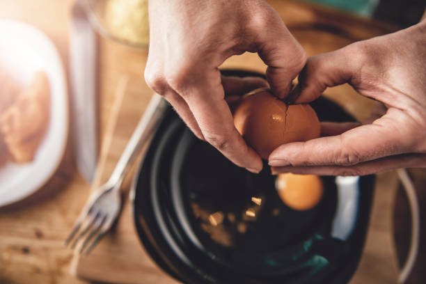 donna che cucina e rompe le uova nel piatto - break eggs domestic kitchen breaking foto e immagini stock