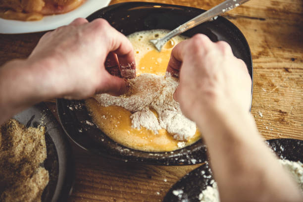 Woman Seasoning Meat A woman is dipping flour coated chicken fillet into an egg mixture. omelet rustic food food and drink stock pictures, royalty-free photos & images