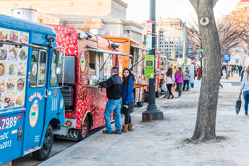 Food trucks on street by National Mall with people buying