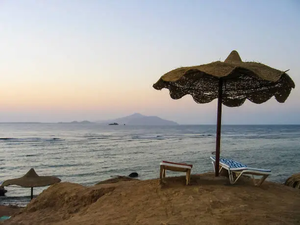 Red Sea in Egypt during sunrise with blue water and beach with umbrella and chairs