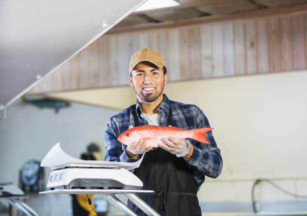 istock Hispanic man working in seafood market, holding fish 642673988