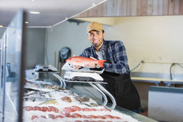 istock Hispanic man working in seafood market, holding fish 642674008