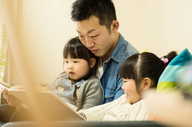 istock Father and sisters looking educational books together at home 642704584