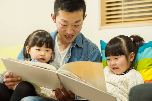 istock Father and sisters looking educational books together at home 642704690
