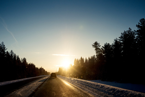 Vinterväg i Sverige med solen som går upp i horizonten och bländar sikten. Vackra färger i soluppgången.