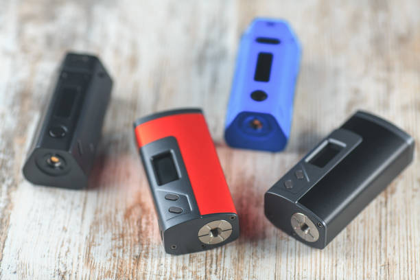 istock Black, blue and red electronic cigarette mods lie on the table. 642708338