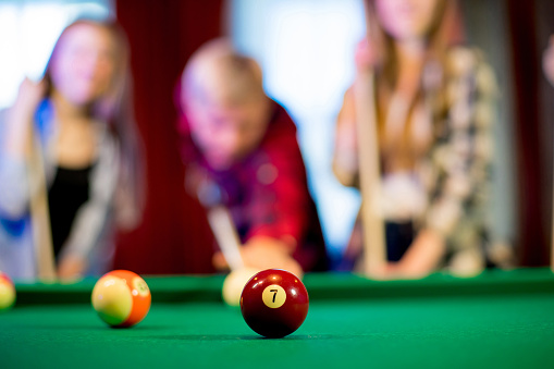 friends playing billiard together in evening. bokeh