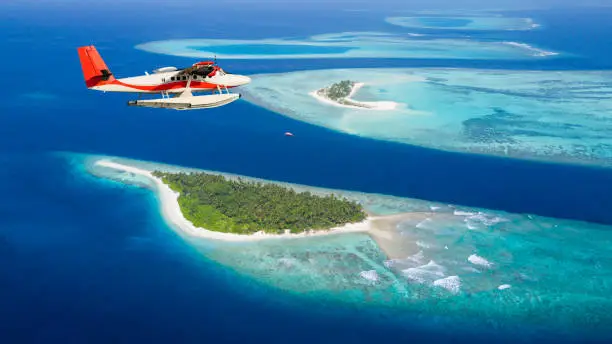 Sea plane flying above Maldives islands, concept of travel and vacation