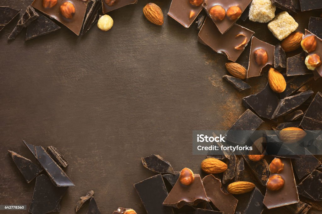 Chocolate background with a space for a text Various types of chocolate pieces crushed on a dark surface, chocolate background with a space for a text, view from above Almond Stock Photo