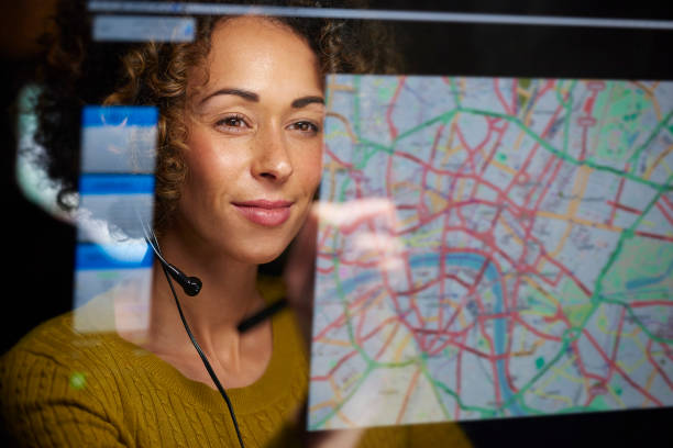 freight dispatcher with digital display a female logistics worker is organising dispatch of freight on her interactive digital map whilst talking on her headset. dispatcher stock pictures, royalty-free photos & images