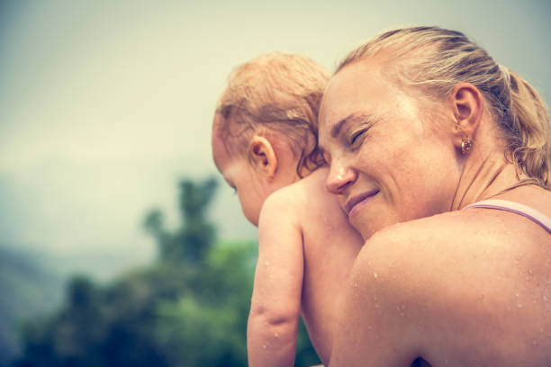 Happy young woman holding her daughter at riverbank