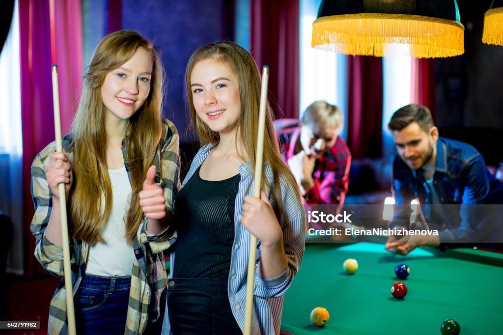 friends playing billiard friends playing billiard together in evening. two boys and two girls Adult Stock Photo