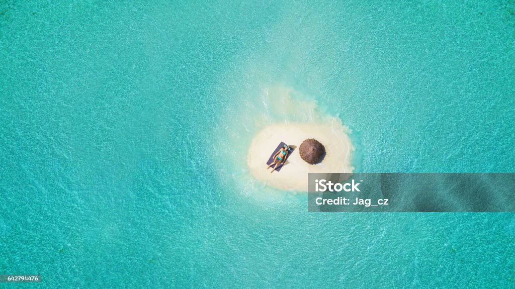 Joven mujer tomando el sol en la pequeña isla de arena - Foto de stock de Isla libre de derechos