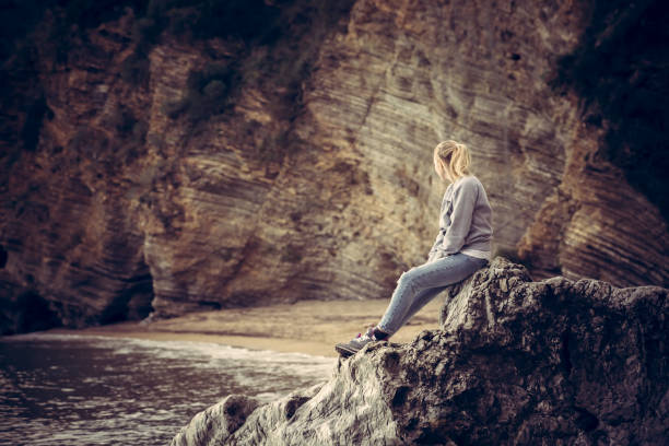 pensive samotna młoda kobieta podróżniczka relaks na dużym klifie na plaży patrząc na dzikie górskie krajobrazy w stylu retro vintage - cliff the way forward forecasting mountain peak zdjęcia i obrazy z banku zdjęć