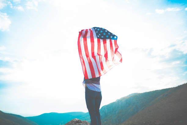 istock Woman holding US flag on mountain 642819596