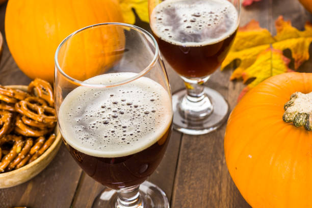 Craft pumpkin beer Craft pumpkin beer in beer glasses with salty pretzels and popcorn. porter photos stock pictures, royalty-free photos & images