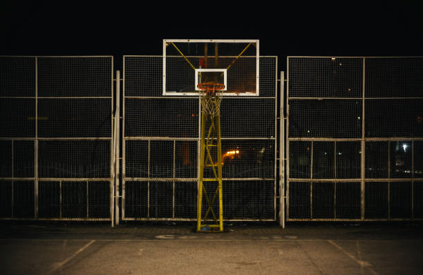 The Basketball Court The basketball court during night, view on basketball hoop and fence. asphalt basketball court stock pictures, royalty-free photos & images
