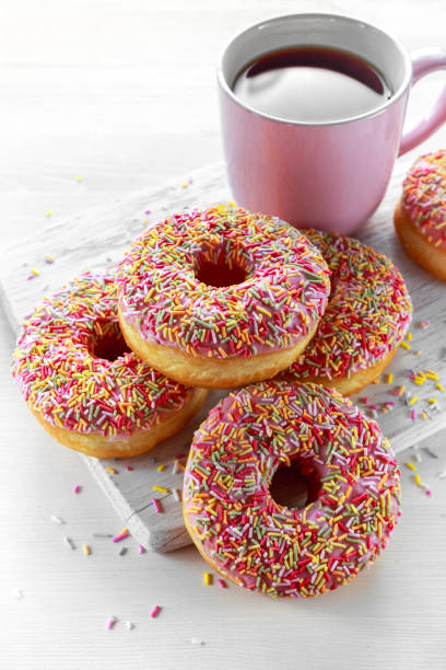 istock Iced doughnut rings with rainbow sparkl strands and cup of coffee, tea 642892120