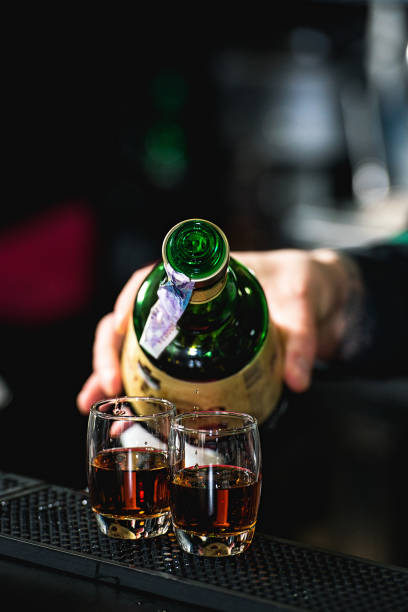 Barman pouring hard spirit into glasses in detail