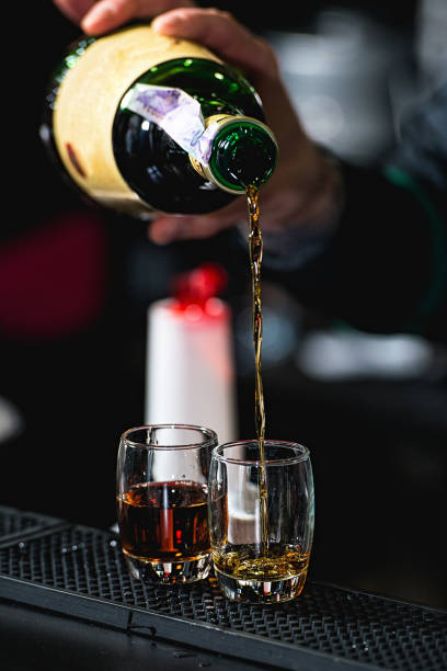 Barman pouring hard spirit into glasses in detail