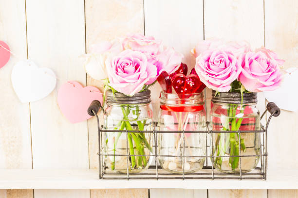 istock Pink roses in jars on rustic wood shelf 642920428