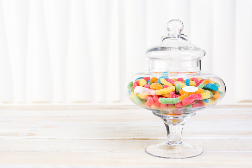 Candies in candy jar on wood table.